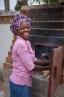 ANGOLA - AFRICA - APRIL 5, 2018 - Black woman standing at furnace with wood and looking at camera — Stock Photo