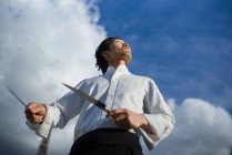 Japanese chef with knives in front of blue sky with clouds — Stock Photo