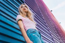 Блондинка молода жінка спирається на синю стіну на вулиці — стокове фото