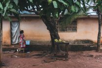 CAMERÚN - ÁFRICA - 5 DE ABRIL DE 2018: mujer étnica de pie con canasta en casa gruñona en la aldea - foto de stock