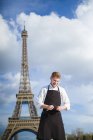 Cozinheiro de cabelo vermelho sorridente com facas em frente à Torre Eiffel em Paris — Fotografia de Stock