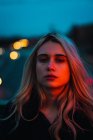 Thoughtful blonde woman looking at camera in dusk — Stock Photo
