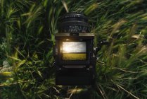 Close-up of Retro photo camera in grass with photo of nature with yellow flowers on display — Stock Photo