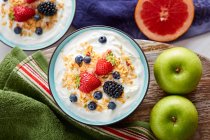 Ciotola di yogurt fresco condita con bacche e cornflakes a bordo — Foto stock