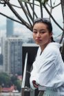 Woman in bathrobe standing on balcony with city view and looking at camera — Stock Photo