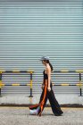 Élégant jeune asiatique femme marche en face de métal mur — Photo de stock