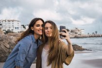 Deux amis souriants prenant selfie sur le bord de la mer — Photo de stock