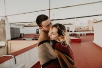 Пара обіймається з ковдрою на терасі — стокове фото