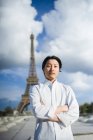 Рыжий повар в белой рубашке стоит перед Эйфелевой башней в Париже — стоковое фото