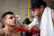 Mãos de médico irreconhecível verificando o olho do boxeador no anel de boxe. — Fotografia de Stock