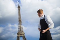 Cozinheiro de cabelo vermelho com camisa branca em pé em frente à Torre Eiffel em Paris — Fotografia de Stock