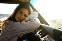 Portrait of young woman lying on wheel in car — Stock Photo