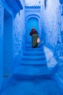 Vecchia donna che sale le scale blu in Marocco — Foto stock