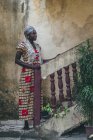 CAMERÚN - ÁFRICA - 5 DE ABRIL DE 2018: Mujer étnica joven y pensativa de pie en las escaleras y mirando hacia otro lado - foto de stock