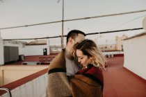 Couple embracing with blanket on terrace — Stock Photo