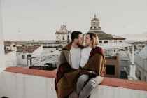 Пара обнимается с одеялом на террасе в старом городе — стоковое фото