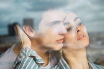 Sensual young man and woman standing together behind window — Stock Photo