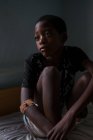 Ангола - Африка - 5 квітня 2018 - задумливою чорний хлопчик, сидячи на ліжку у себе вдома і дивитися вбік — стокове фото
