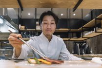 Chef preparing dish with chopsticks in restaurant — Stock Photo