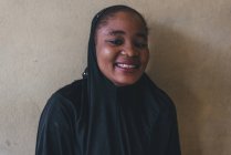 Kamerun - Afrika - 5. April 2018: fröhliche ethnische Frau steht an der Wand — Stockfoto
