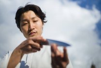 Japanese chef checking knife in front of blue sky — Stock Photo