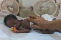 Kamerun - Afrika - 5. April 2018: Hand berührt neugeborenes ethnisches Kind in steriler Box im Krankenhaus — Stockfoto