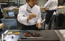 Chef preparing dish with chopsticks in restaurant — Stock Photo