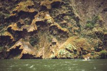 Río tranquilo que fluye en el cañón de Sumidero con barco turístico en el fondo, Chiapas, México - foto de stock