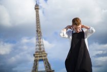 Red-Hair cozinheiro vestindo avental preto em pé em frente à Torre Eiffel em Paris — Fotografia de Stock
