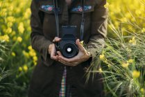 Mulher de jaqueta segurando dispositivo de foto na natureza — Fotografia de Stock