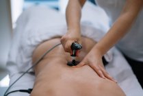 Физиотерапевт лечит человека, используя оборудование для радиотерапии — стоковое фото