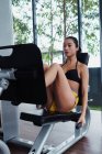 Pretty Asian woman pushing machine and exercising in gym — Stock Photo