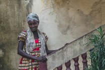 CAMERÚN - ÁFRICA - 5 DE ABRIL DE 2018: Mujer étnica joven y reflexiva de pie en las escaleras y mirando a la cámara - foto de stock