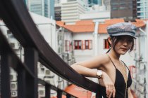 Young Asian woman in stylish clothes leaning on fence in city — Stock Photo