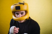 Homem lutador confiante com braços enfaixados no capacete olhando para a câmera. — Fotografia de Stock