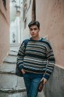 Молодий впевнений підліток в светрі, стоячи на вулиці і дивлячись на камеру — стокове фото