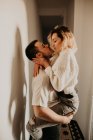 Пристрасний чоловік і жінка обіймаються і цілуються на стіні вдома — стокове фото