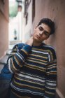 Молодой задумчивый подросток в свитере стоит на городской улице — стоковое фото
