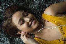 Smiling woman with earphones lying on floor — Stock Photo
