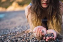 Gros plan des mains féminines avec une poignée de cailloux sur la plage — Photo de stock