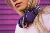 Nahaufnahme einer jungen blonden Frau mit lila Kopfhörern — Stockfoto