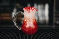 Jarra de vidrio llena de limonada refrescante de bayas rojas en un mostrador en el bar. - foto de stock