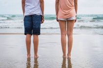 Legs of teenager friends standing on beach — Stock Photo