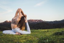 Donna che allunga e fa yoga sul prato in natura — Foto stock