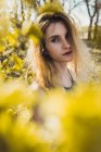 Портрет молодої дівчини, що стоїть в кущі зі свіжими паростками весняного листя — стокове фото