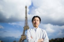 Retrato del chef japonés con los brazos cruzados de pie frente a la Torre Eiffel en París - foto de stock