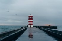 Старый красно-белый маяк в океане, Порту, Португалия — стоковое фото