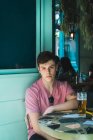Впевнений молодий чоловік сидить зі склянкою пива за столом — стокове фото