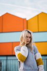 Thoughtful blonde woman standing at colorful houses — Stock Photo