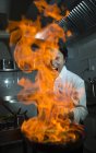 Cozinheiro animado fazendo um flambe na cozinha do restaurante — Fotografia de Stock